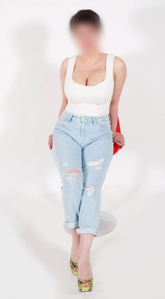 Persona con jeans rasgados y top blanco, fondo blanco.