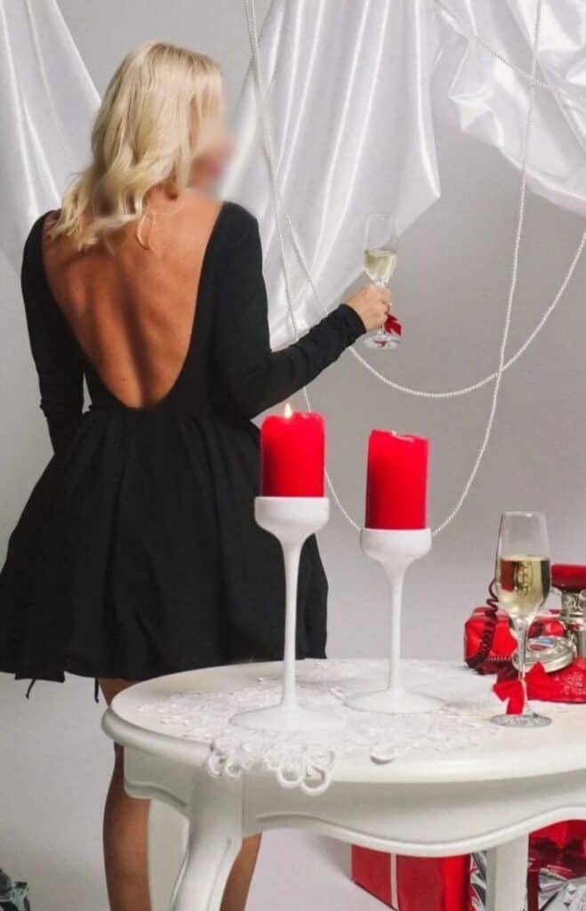 Mujer elegante con vestido negro brindando en fiesta