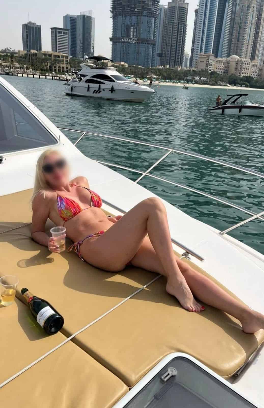 Mujer en bikini relajándose en yate con champán